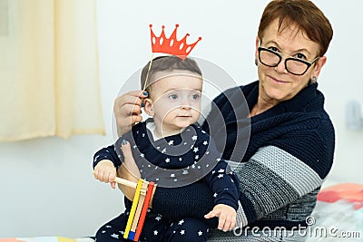 Party, Purim. Senior woman having fun with grandson, holding funny crown on a stick Stock Photo