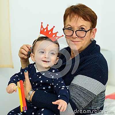 Party, Purim. Senior woman having fun with grandson, holding funny crown on a stick Stock Photo