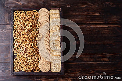 Party snacks, box with cookies, crackers and mini salted pretzels on a dark wooden background Stock Photo