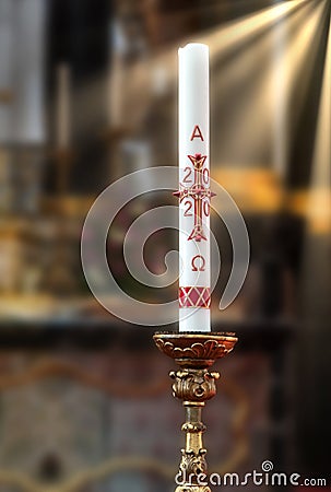 Paschal candle Osterkerze 2020 on the altar. Blurred background with sun rays Stock Photo