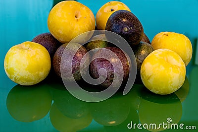 Pasiflora fruits and large yellow plums on on green glass table, selective focus Stock Photo