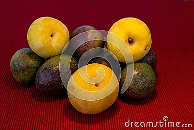 Pasiflora fruits and large yellow plums on red cloth napkin background, selective focus Stock Photo