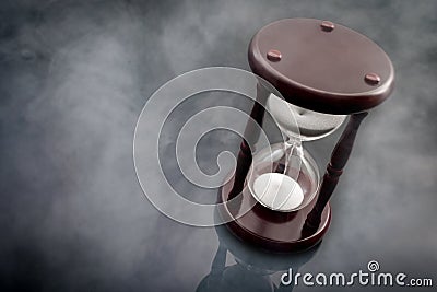 The passage of time and the ephemerality of life concept with hourglass surrounded by smoke or gof on a dark background with copy Stock Photo