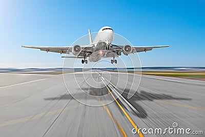 Passenger aircraft with a cast shadow on the asphalt landing on a runway airport, motion blur. Stock Photo