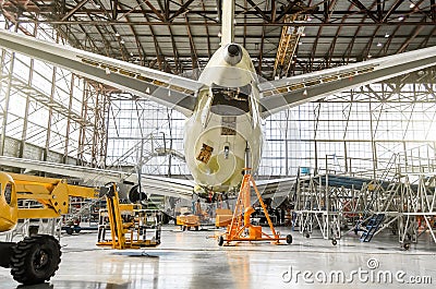 Passenger aircraft on service in an aviation hangar rear view of the tail, on the auxiliary power unit. Stock Photo