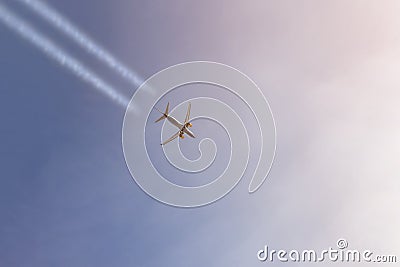 Passenger airplane flying high in clear sky leaving white trails. Big plane flying during sunset time with dramatic sky on backgro Stock Photo