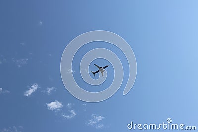 A passenger airplane flying high in the sky among the clouds. Air liner leaving a trace of exhaust gases glowing in the sun. Ecolo Stock Photo
