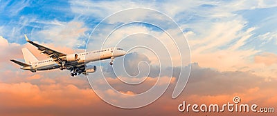 Passenger airplane is landing approach gear released, against sunset sky clouds, panorama. Travel aviation, flight, trip Stock Photo