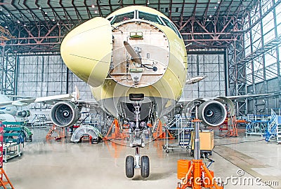 Passenger airplane on maintenance of engine and fuselage check repair in airport hangar. With an open hood on the nose under the c Stock Photo