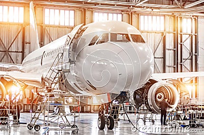 Passenger commercial airplane on maintenance of engine turbo jet and fuselage repair in airport hangar. Aircraft with open hood on Stock Photo