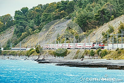 Passenger double deck train moves along the Black sea beach. Sochi Stock Photo