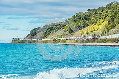 Passenger double deck train moves along the Black sea beach. Sochi Stock Photo