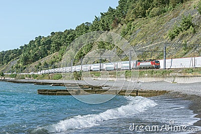 Passenger double deck train moves along the Black sea beach. Sochi Stock Photo