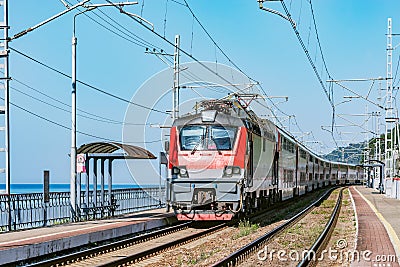 Passenger double deck train moves along the platform and Black sea shore. Sochi Stock Photo