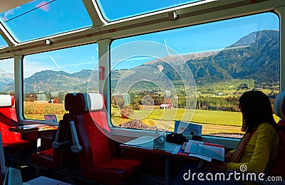 A passenger enjoying the idyllic scenery of Swiss countryside through the wide panoramic windows Editorial Stock Photo