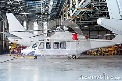 Passenger helicopter and airplanes under maintenance. Checking mechanical systems for flight operations. Rotorcraft and aircrafts Stock Photo