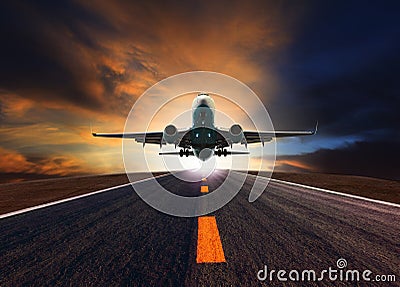 Passenger jet plane flying over airport runway against beautiful Stock Photo