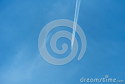 Passenger plane on a background of clear blue sky. A long stream of smoke escapes from the engines of a jet aircraft. Condensation Stock Photo
