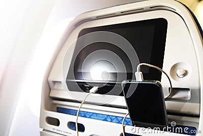Passenger on a plane using the charger for charge smart phone during flight. Charging station on plane Stock Photo