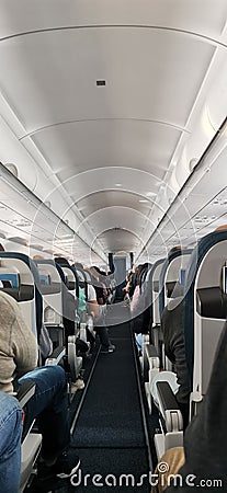 Passenger seat, aircraft interior with passengers sitting on the seats. Travel concept. Airplane cabin with people. Stock Photo