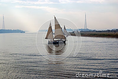 Passenger ship with two Latin sails, typical of the Nile River, sailing through the center of the river. Banks full of vegetation Stock Photo