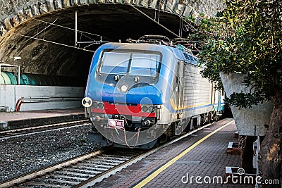 Passenger train driving out from tunnel near Riomaggiore town, Cinque Terre, Italy Stock Photo