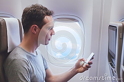 Passenger using mobile phone smartphone in the airplane Stock Photo