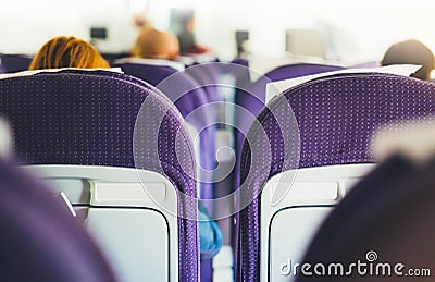 Passengers are sitting in the blue armchairs of the aircraft during the flight, the view from the back of tourists flying into Stock Photo