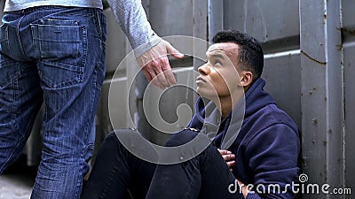 Passing by man offering helping hand to street child, kindness and charity Stock Photo