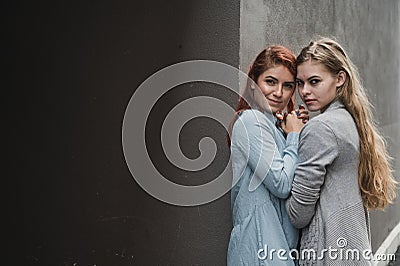 Passionate loving lesbian couple. Two beautiful young women hugging tenderly outdoors against a gray wall. LGBT commune Stock Photo