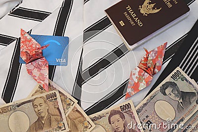 Passport,banknotes, credit card and origami paper birds place on japanese pajamas call as yukata Stock Photo