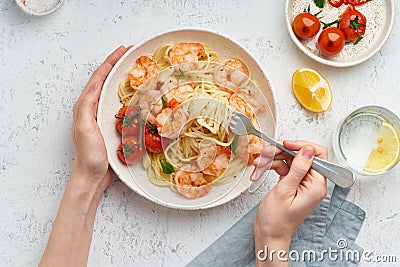 Pasta bavette with fried shrimps, bechamel sauce. Woman hands in frame, girl eats pasta, top view Stock Photo