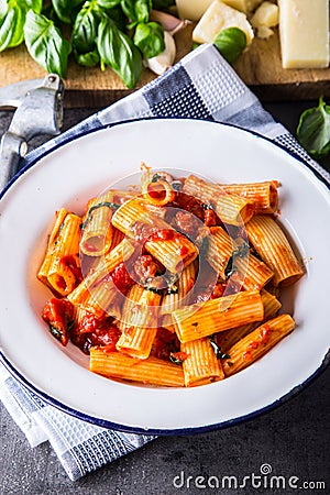 Pasta. Italian and Mediterrannean cuisine. Pasta Rigatoni with tomato sauce basil leaves garlic and parmesan cheese. Stock Photo
