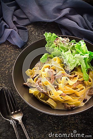 Pasta with meat and green salad in ceramic bowl. Stock Photo