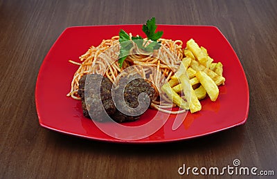 Pasta, meatballs and potatoes on a red plate on the table Stock Photo