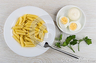 Pasta in plate, parsley, mayonnaise and boiled eggs in saucer Stock Photo