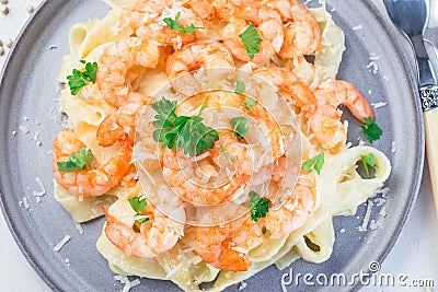 Pasta with shrimps in creamy parmesan cheese and garlic sauce garnished with parsley, fettucini alfredo, horizontal, top view, Stock Photo