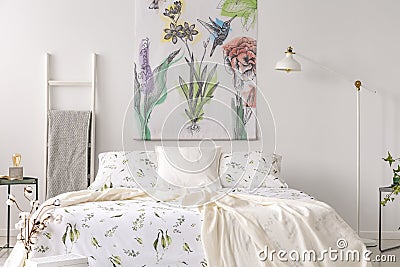 A pastel bedroom interior with a bed dressed in green plants pattern white linen. Fabric painted in flowers and birds on the backg Stock Photo