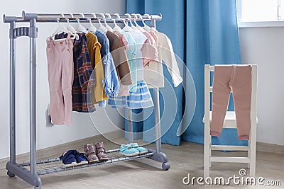 Pastel color children`s clothes in a Row on Open Hanger indoors. Clothes for little ladies hung in the children`s room Stock Photo