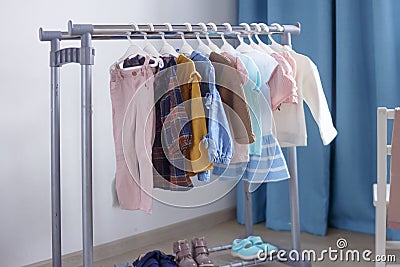 Pastel color children`s clothes in a Row on Open Hanger indoors. Clothes for little ladies hung in the children`s room Stock Photo