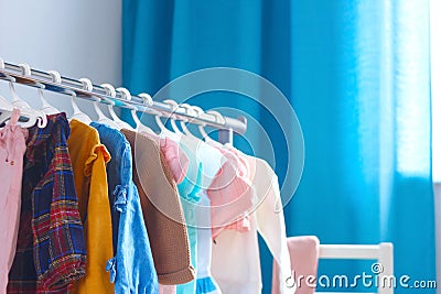 Pastel color children`s clothes in a Row on Open Hanger indoors. Clothes for little ladies hung in the children`s room Stock Photo