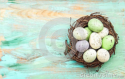 Pastel colored easter eggs in nest on wooden background Stock Photo