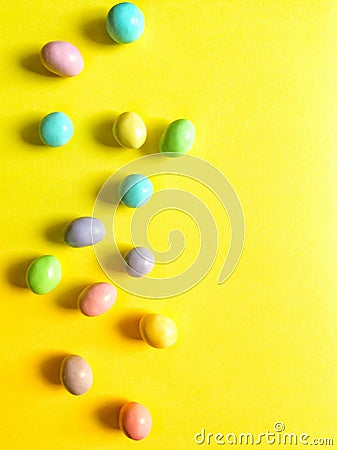 Pastel Easter candies on bright yellow background Stock Photo