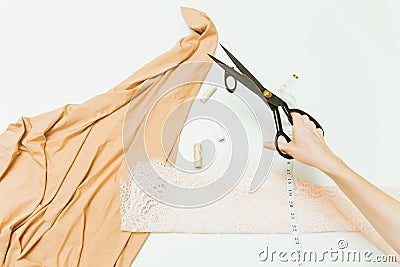 Pastel fabric, threads, drawing and scissors in the tailor`s hand, top view. Layout of sewing items Stock Photo