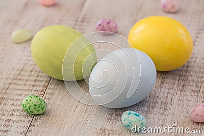 Pastel Painted Easter Eggs and Jelly Beans on White Wood Background Stock Photo