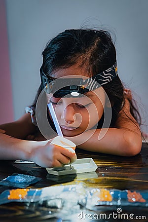 Pasting gemstones, a little girl is making artwork with her own hands Stock Photo