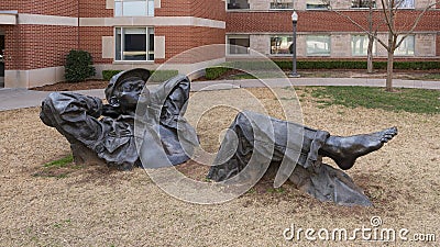 `Pastoral Dreamer`, a larger than life size bronze statue of a man lying in the grass on the campus of the University of Oklahoma. Editorial Stock Photo