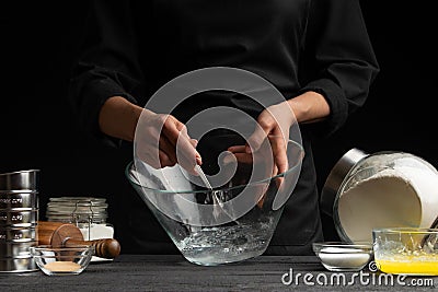 A pastry chef or baker prepares the dough by whipping with a spoon, for sweets, rolls or Italian pizza or pasta. Freeze in motion Stock Photo