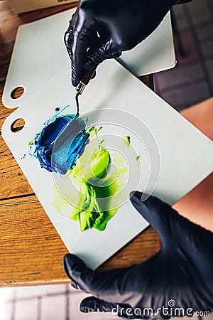 Pastry chef in black rubber gloves stirs colored cream with spatula to decorate cake. food coloring for cream Stock Photo