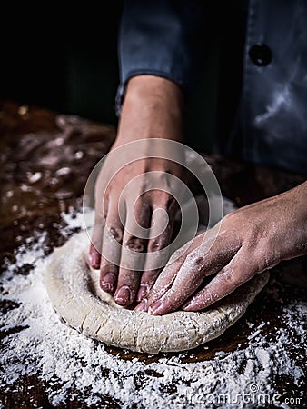 Pastry chef hand kneading Raw Dough with sprinkling white flour Stock Photo